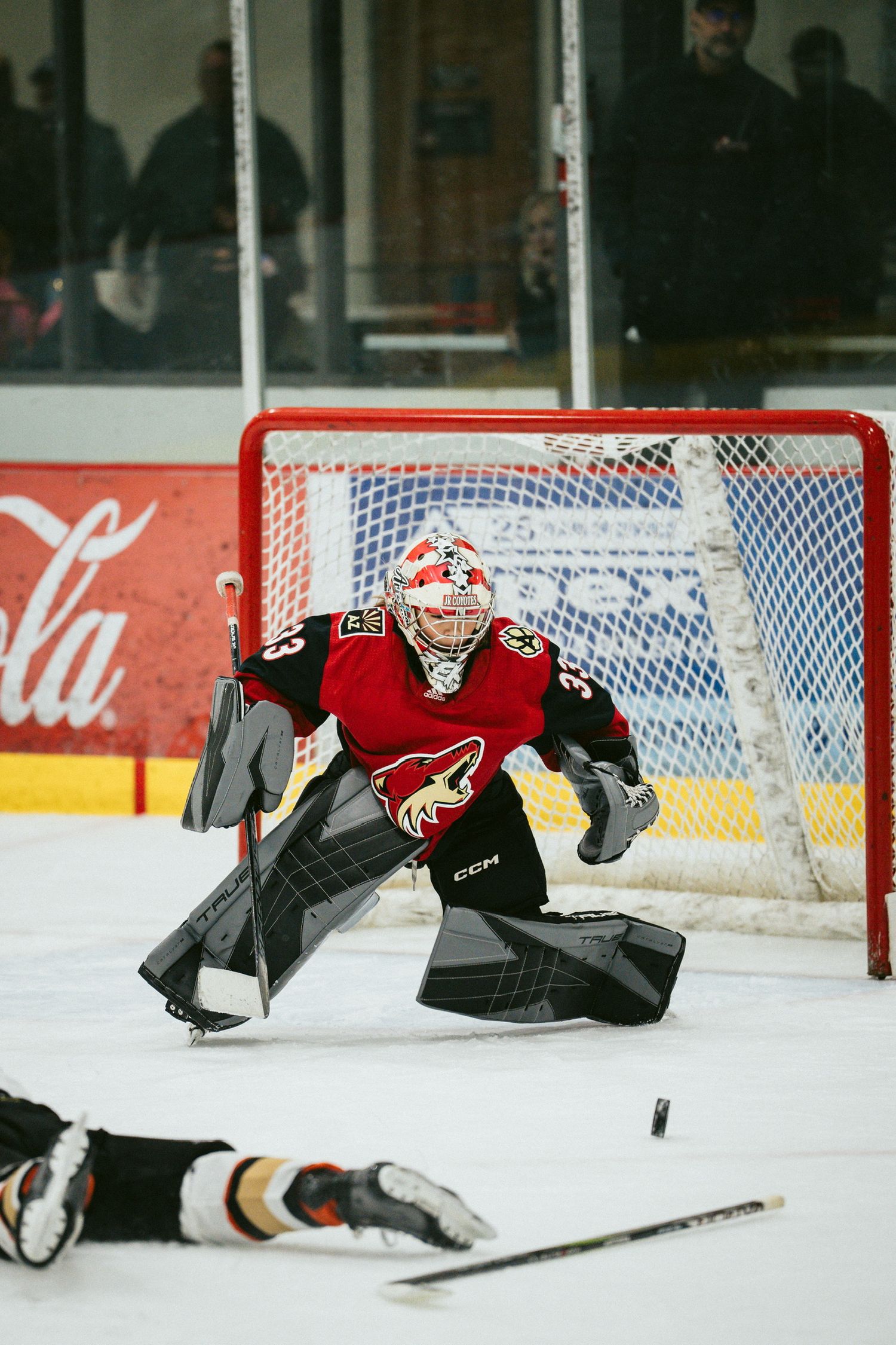 Goalie making dramatic diving save during hockey game.