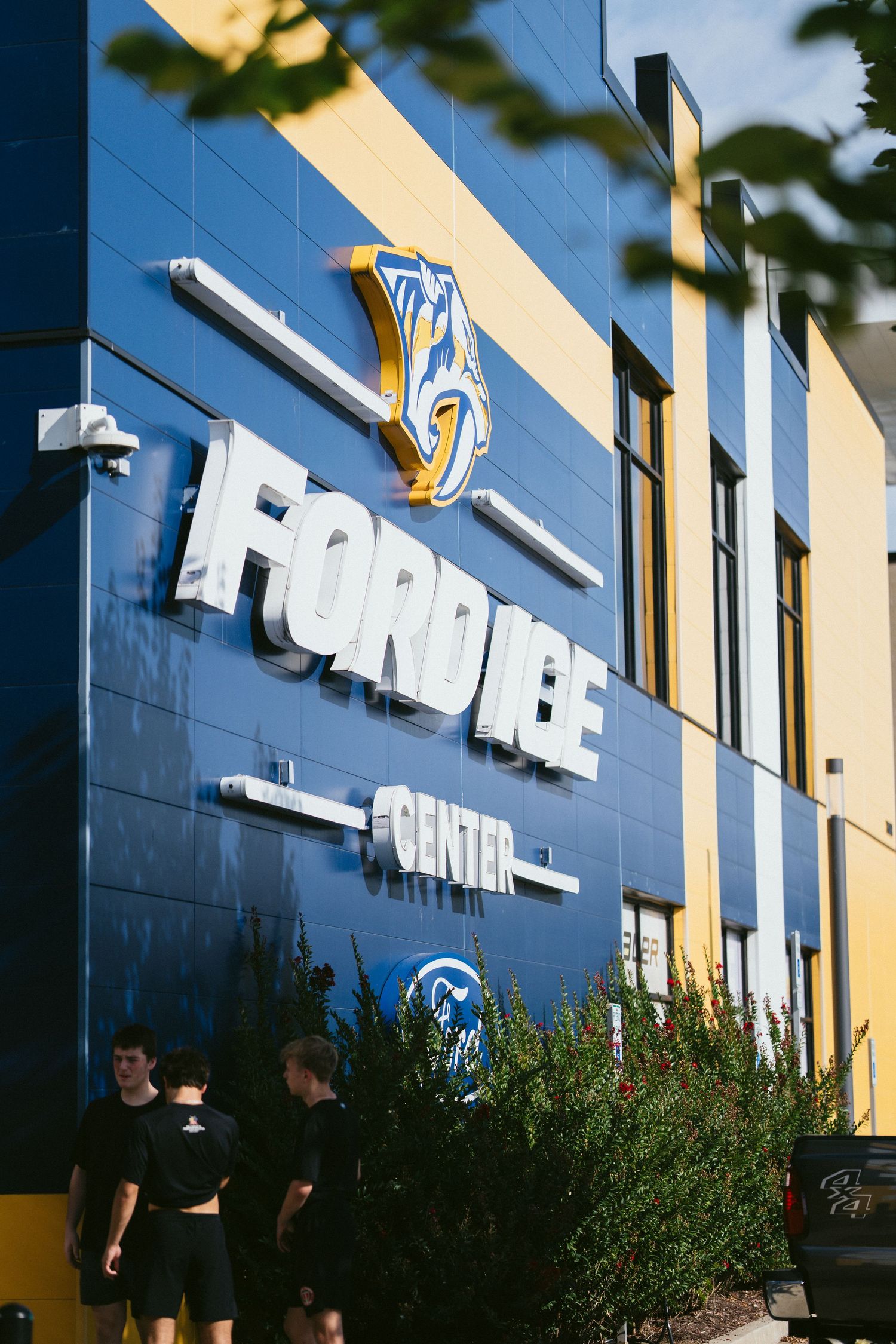 The exterior of Ford Ice Center in Nashville, featuring blue and yellow branding and the Predators logo.