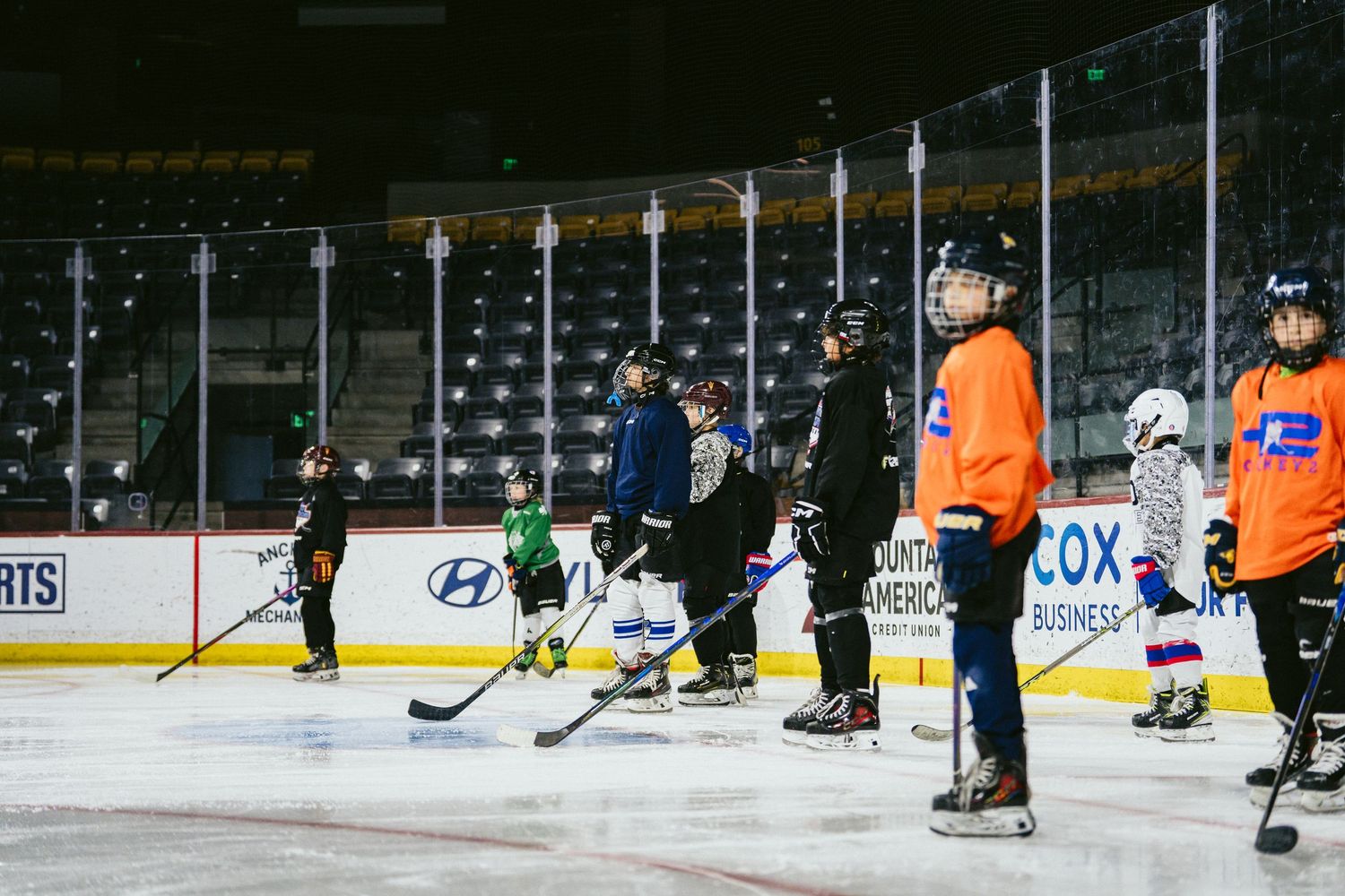 Young youth hockey players practice skating drills on an indoor ice rink during a youth hockey clinic.