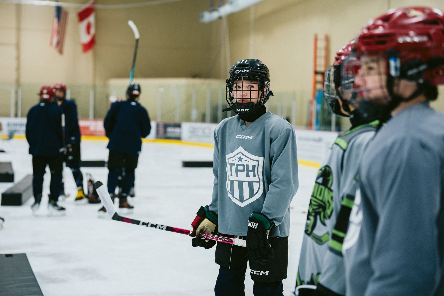 Young hockey players in full gear practice drills at an indoor rink during a TPH hockey training camp.