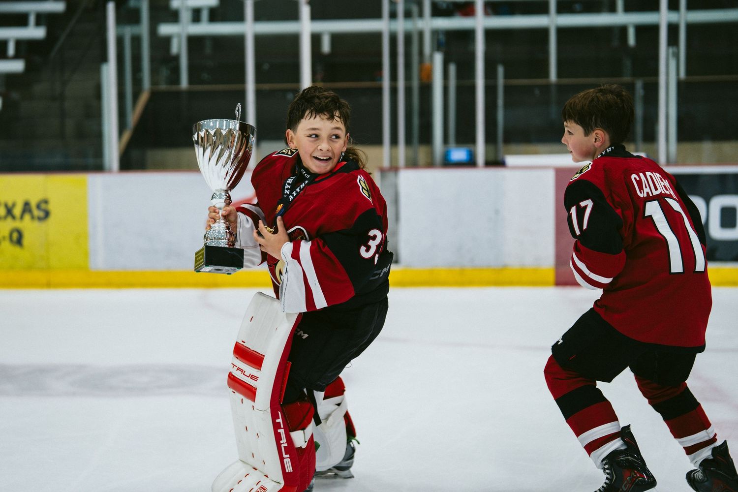 Ice hockey players in red and black jerseys compete during an intense match on the rink.