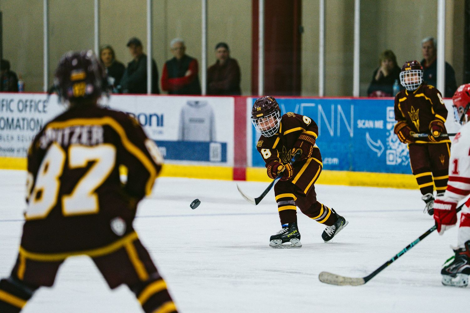 Hockey players in black and gold jerseys position themselves during gameplay on the ice.