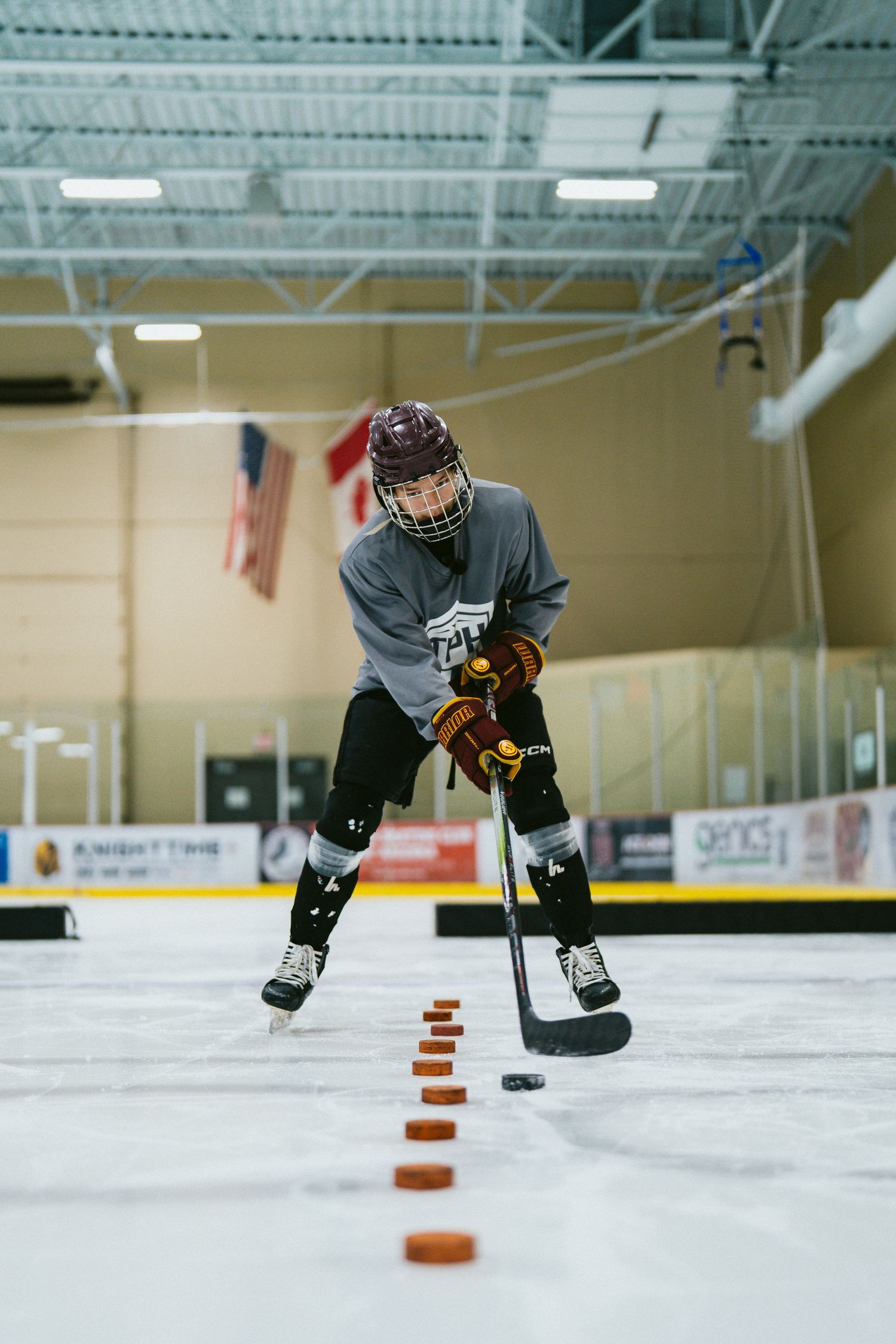 Young hockey player practicing puck control drills on ice rink with lined pucks.
