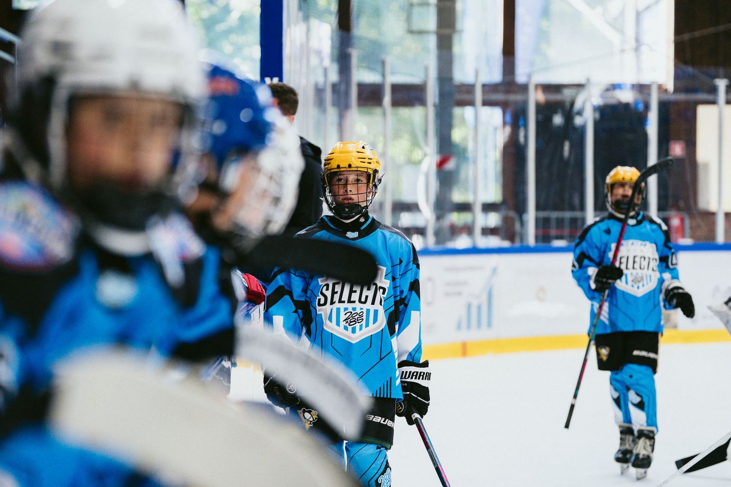 Youth hockey players in blue Select jerseys skate on an indoor ice rink during a practice or game session.