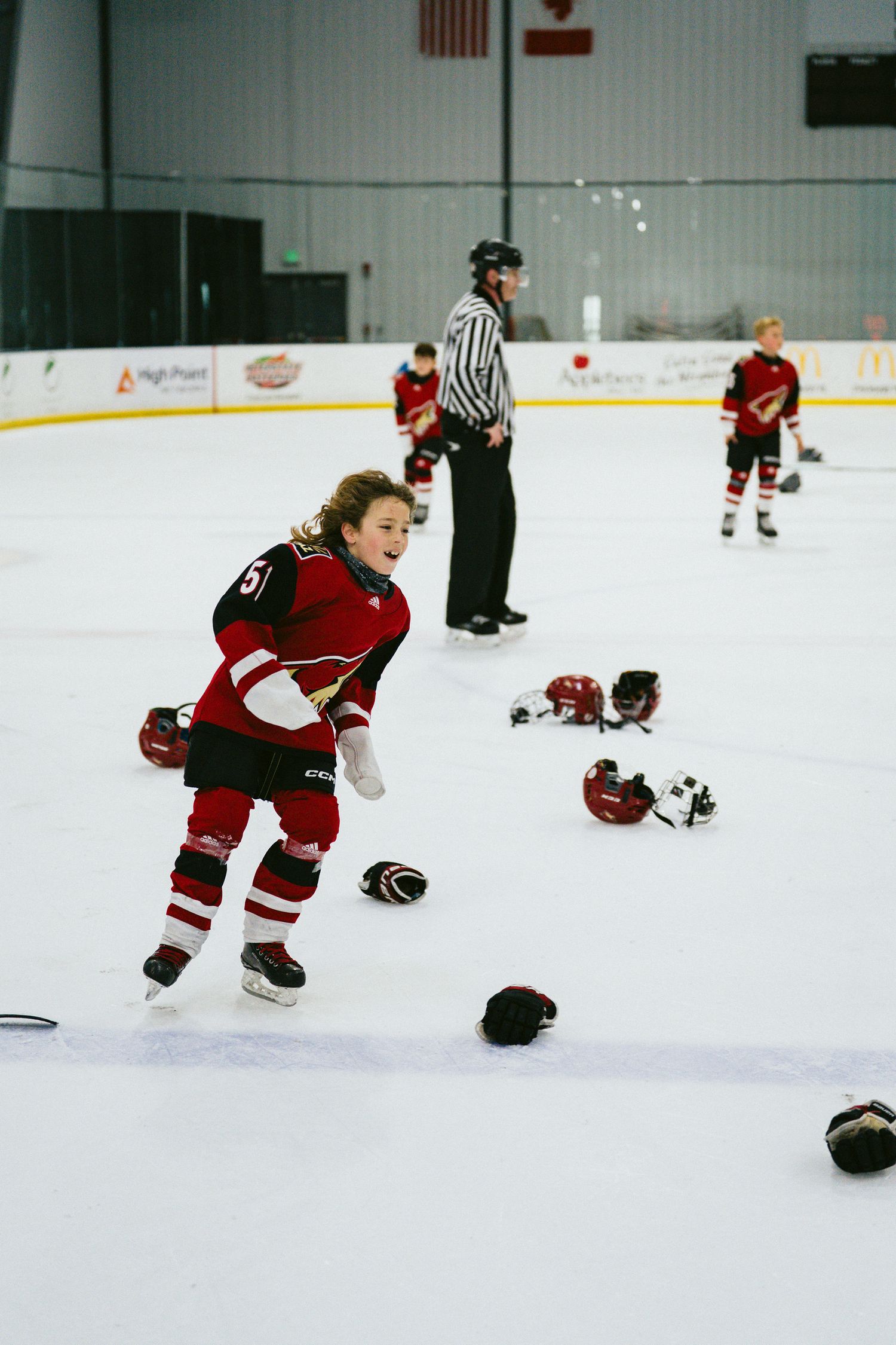 Youth hockey players in red jerseys practicing skating drills on the ice.