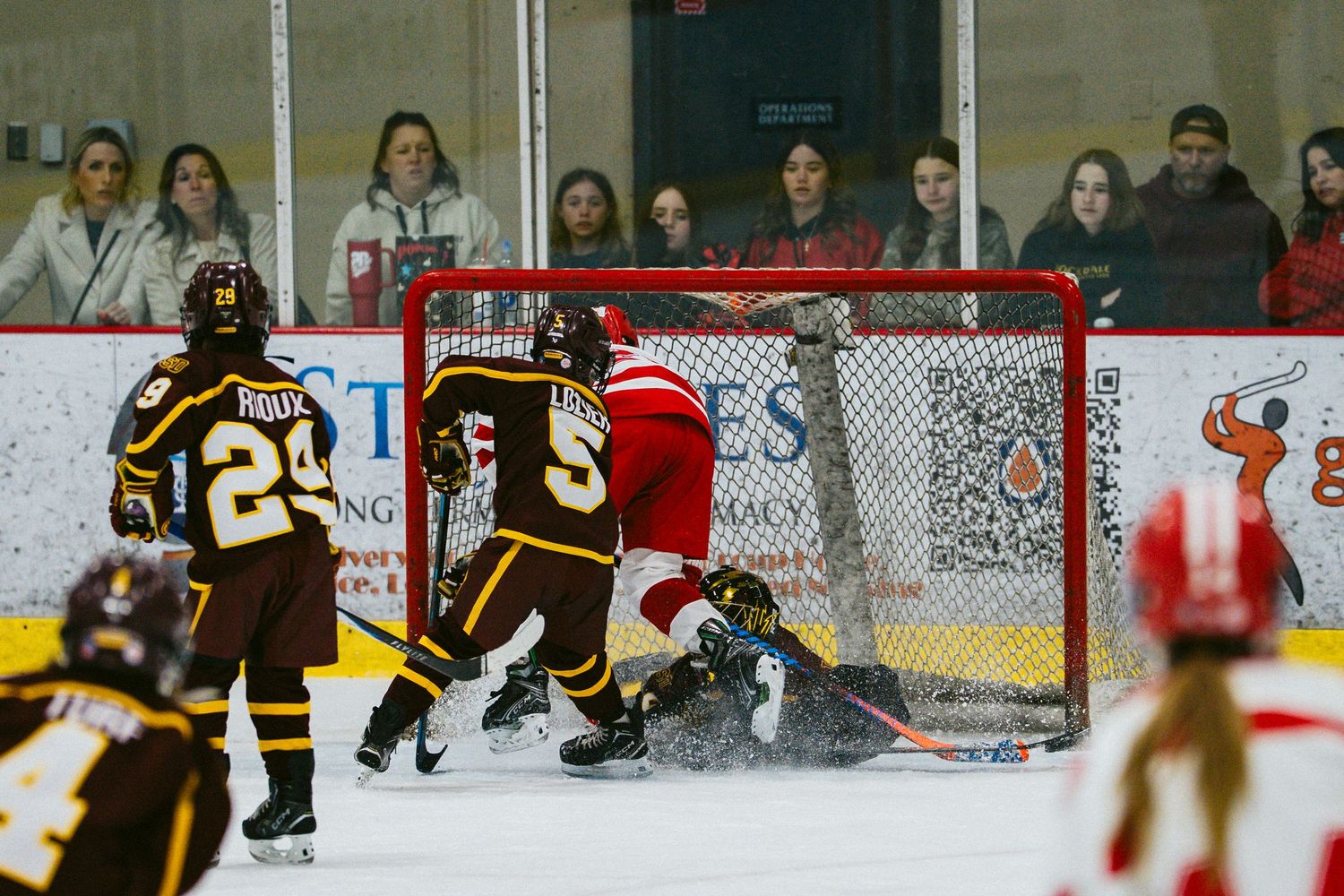 Wide view of hockey rink showing spectators and players during youth game.
