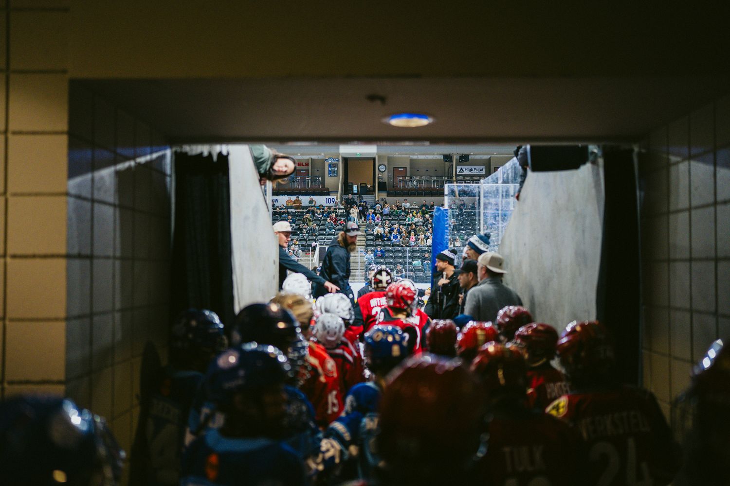 Crowded hockey arena hallway filled with players and spectators.