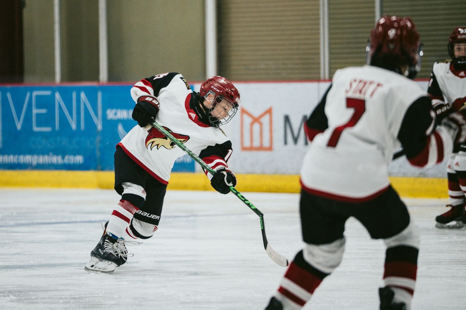Hockey player in white and red uniform taking a shot during game.