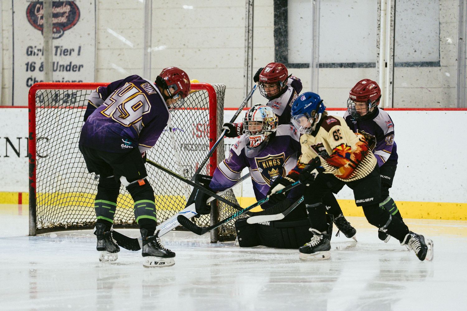 Young hockey players battle for the puck near the goal during an intense youth ice hockey game.