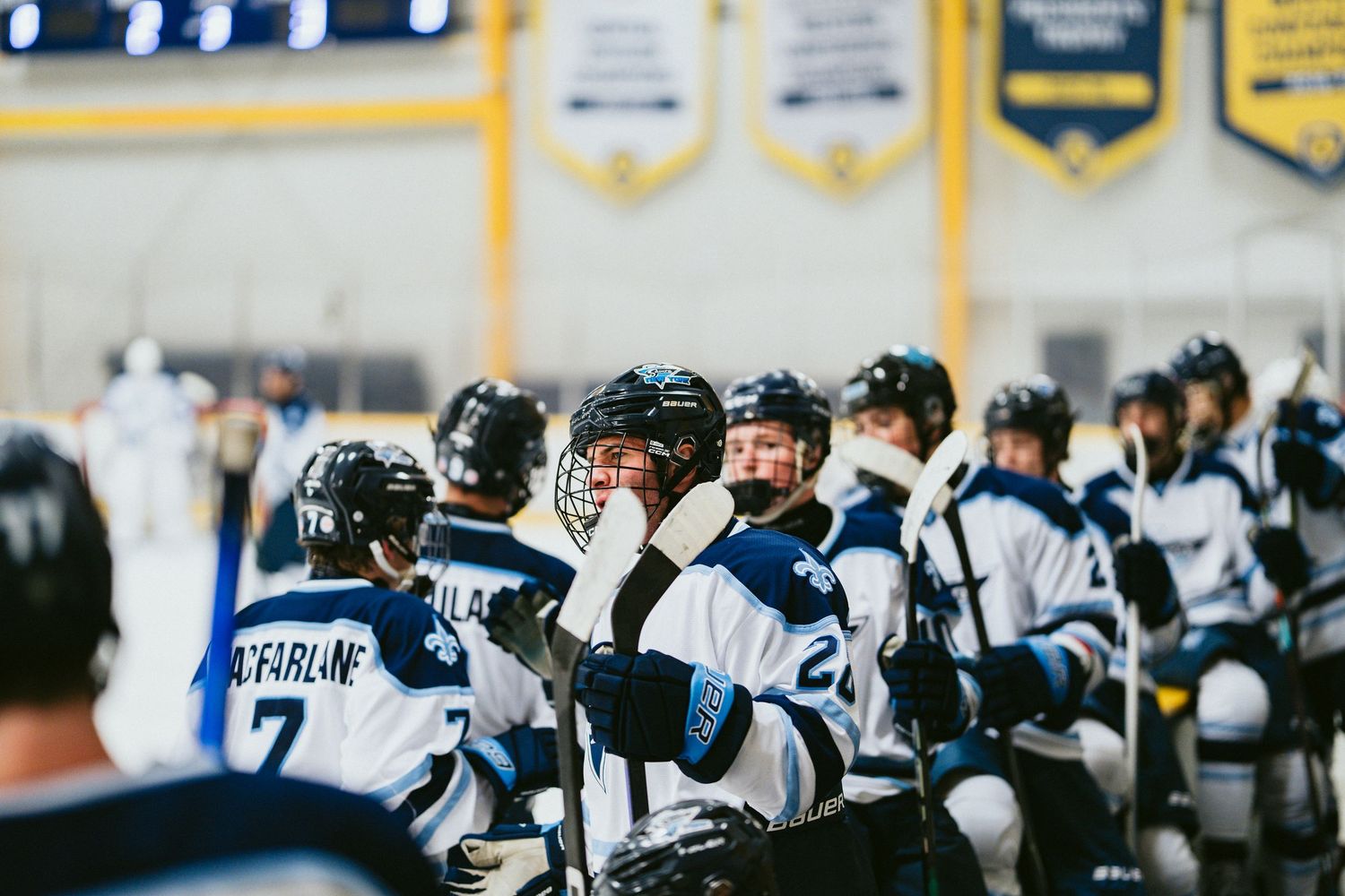 Ice hockey team in blue and white uniforms huddles together on rink during game.