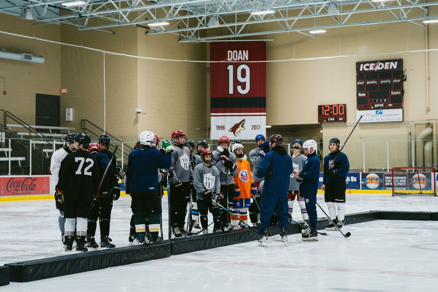 Large group of hockey players gathered for coaching session under Doan 19 jersey at Ice Den.