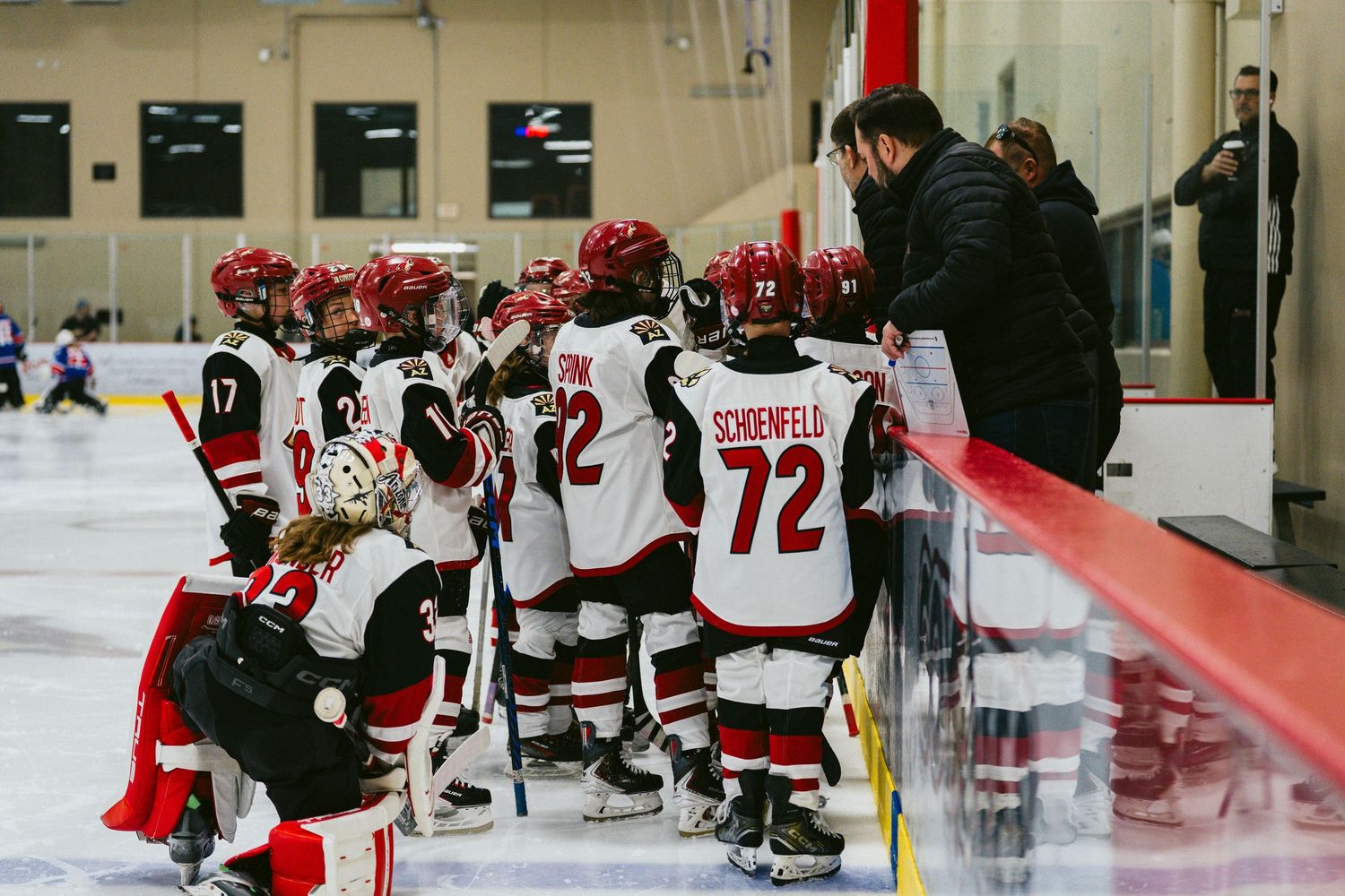 Hockey players in red and white jerseys gather on the ice rink during a game.