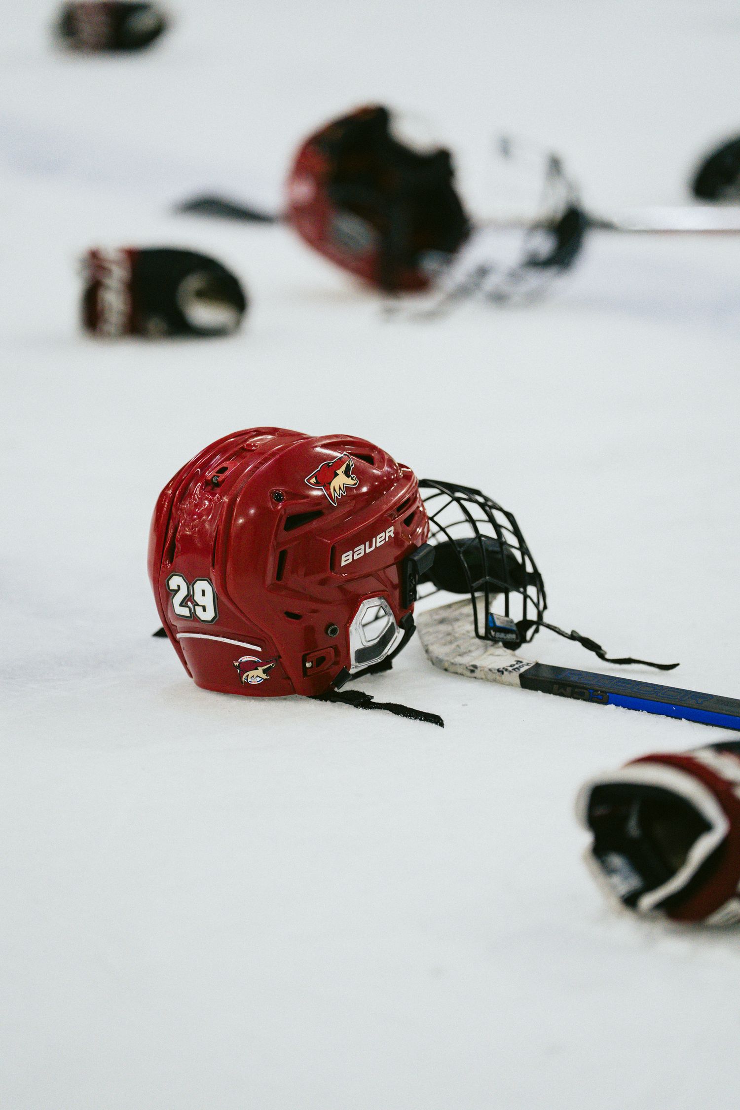 Red hockey helmets and equipment scattered across white ice surface.