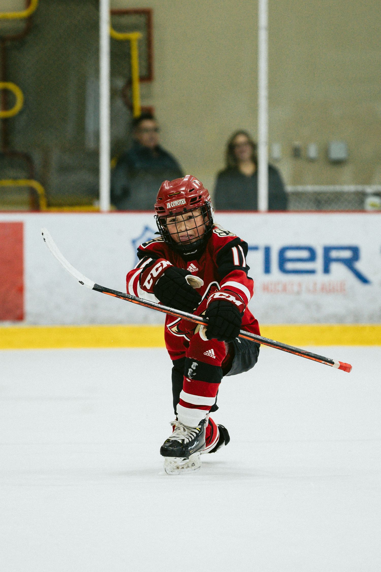 Hockey player in red jersey performs impressive diving maneuver during game.