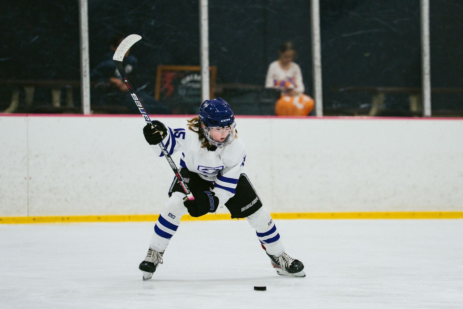 Young hockey player executes dynamic skating move while controlling puck on ice.