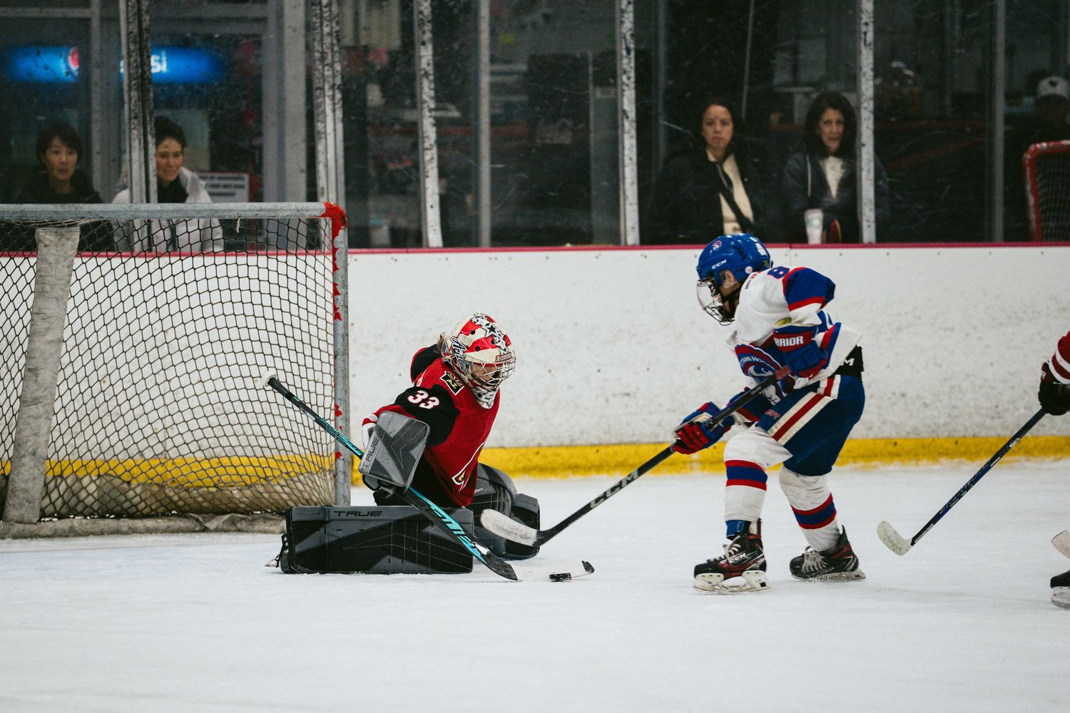 Hockey players in action during fast-paced game on indoor rink.