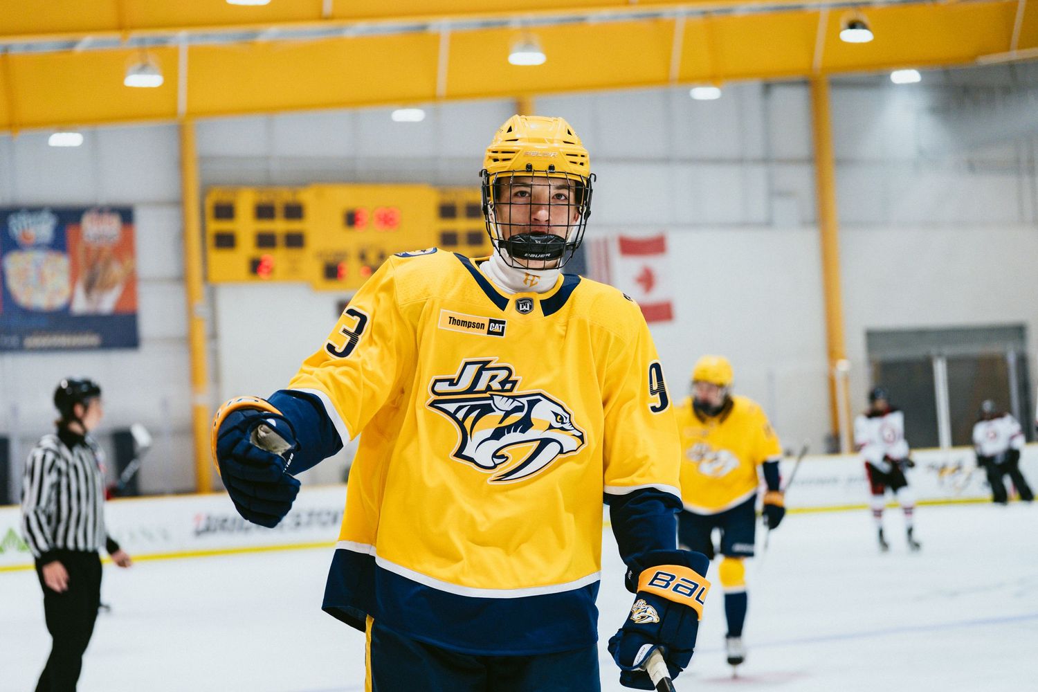 Hockey player in yellow Nashville Predators jersey smiling on indoor ice rink during practice session.