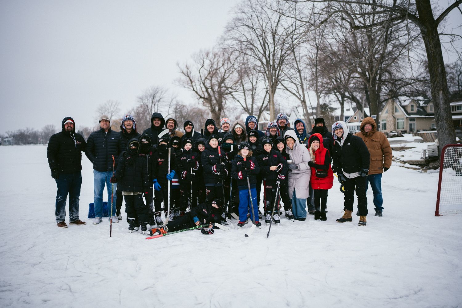 Group photo of hockey players and supporters on a snowy field.