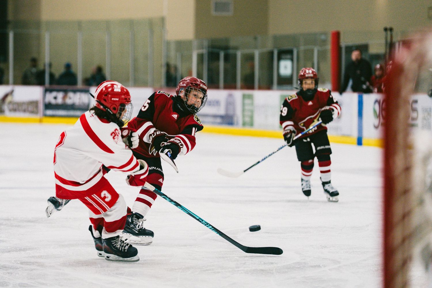 Close-up of hockey players' legs and sticks on ice during gameplay.