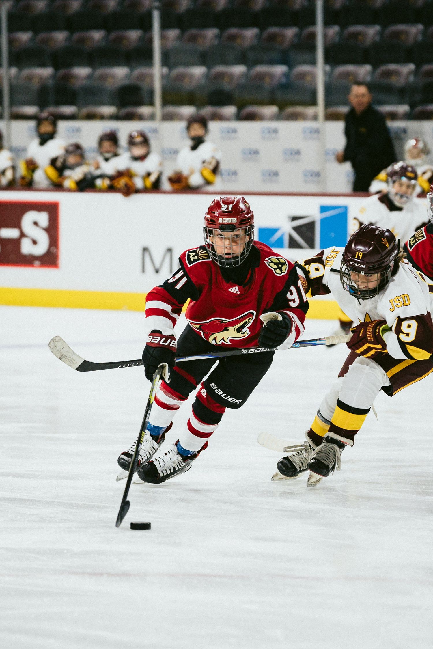 Hockey players from opposing teams race across the ice during competitive match.