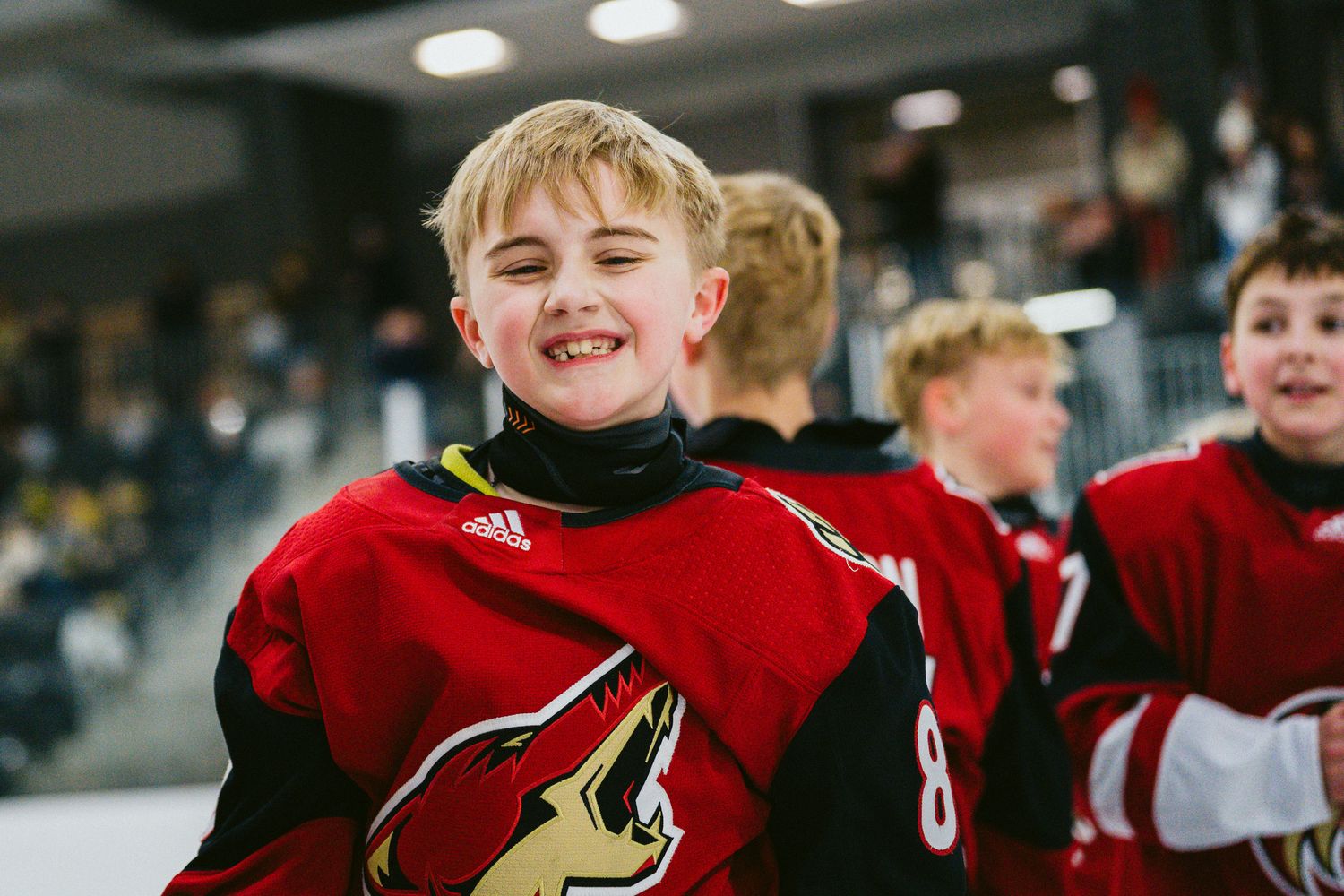 Youth hockey team in red jerseys celebrating together on the ice.