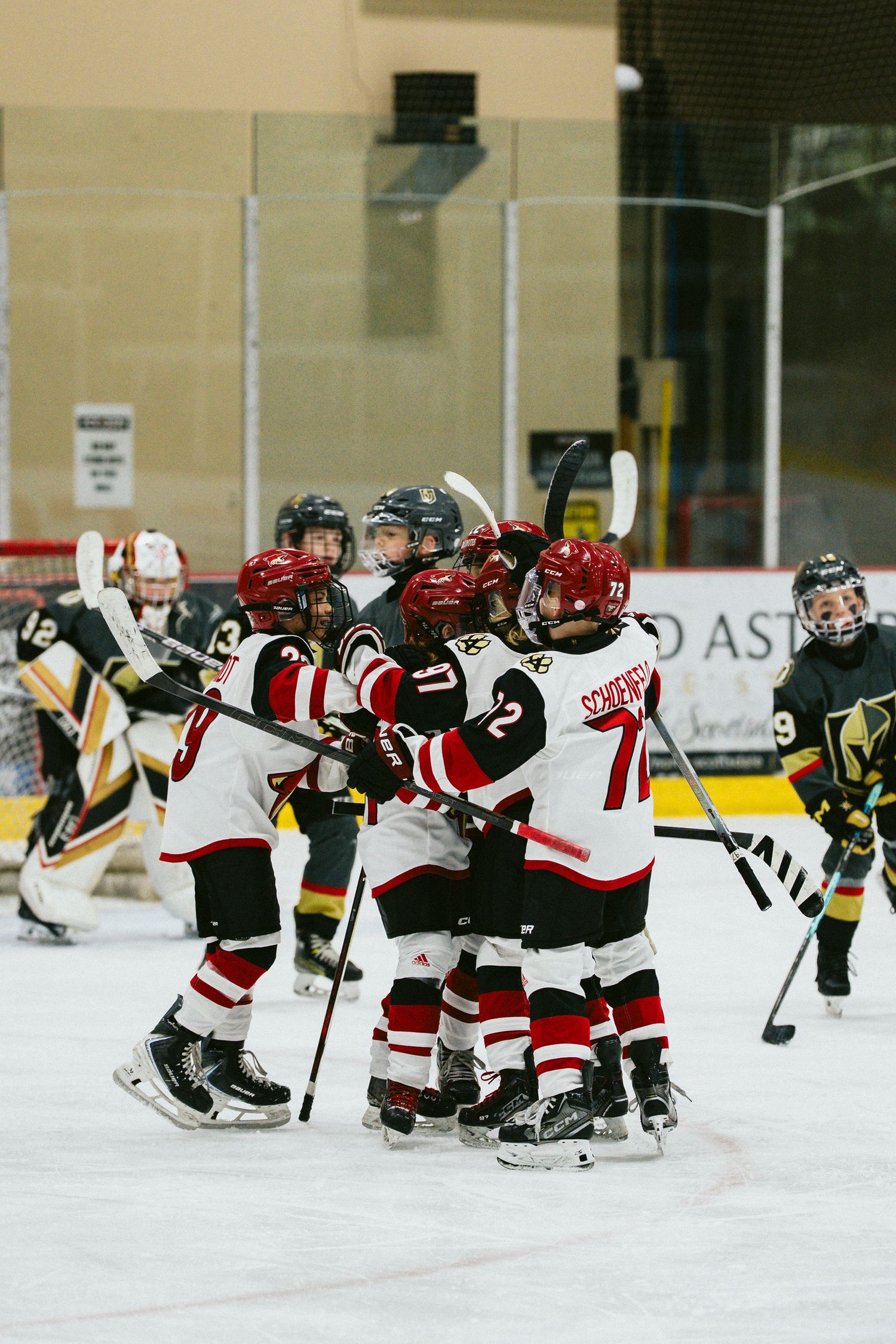 Two youth hockey teams face off on the ice during an intense match.