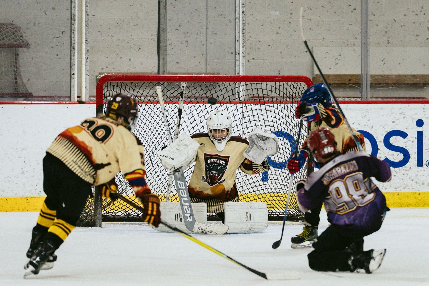 Ice hockey players in action near the goal net during an intense game at an indoor rink.