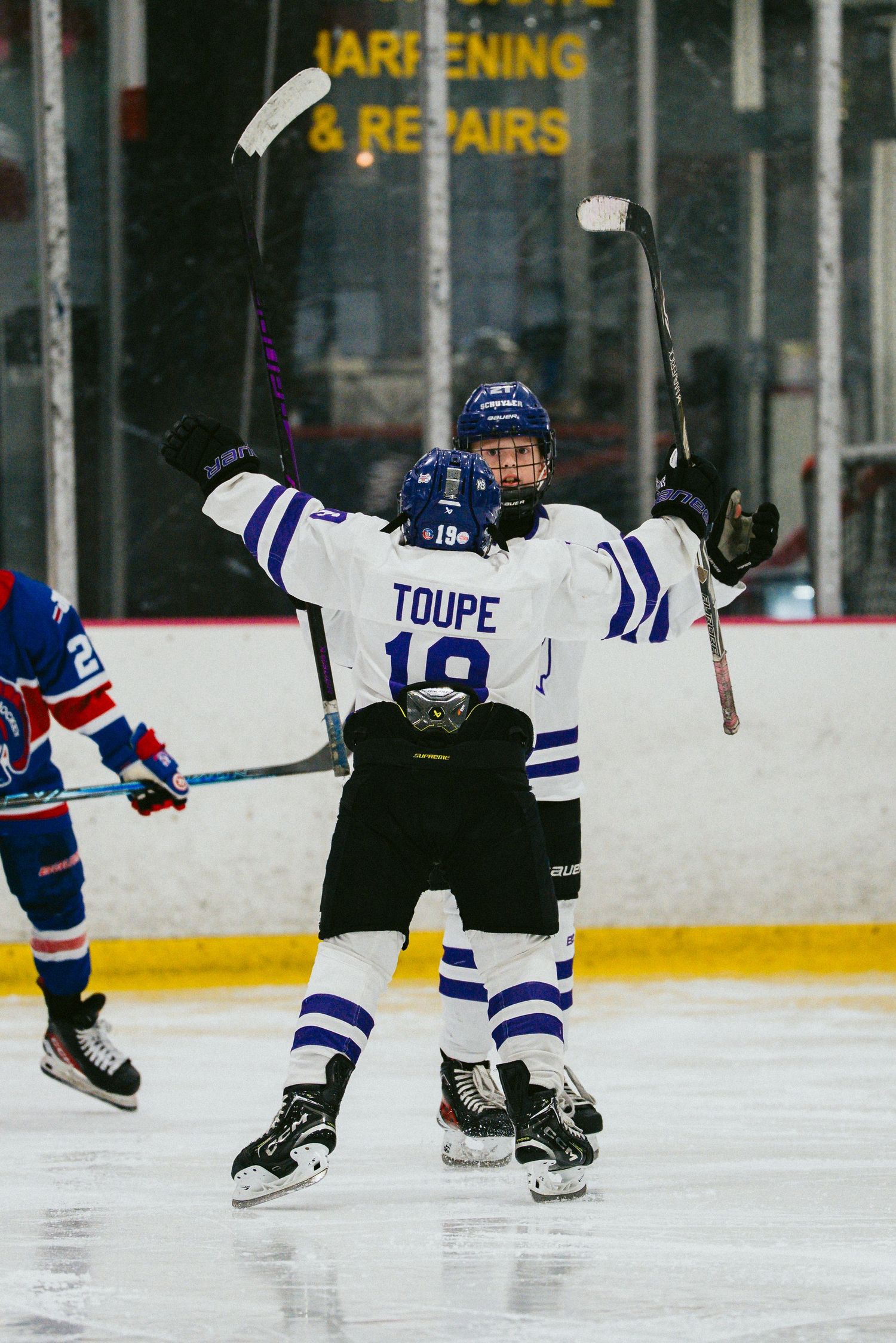 Hockey players celebrate a goal with raised sticks on the ice during a game.