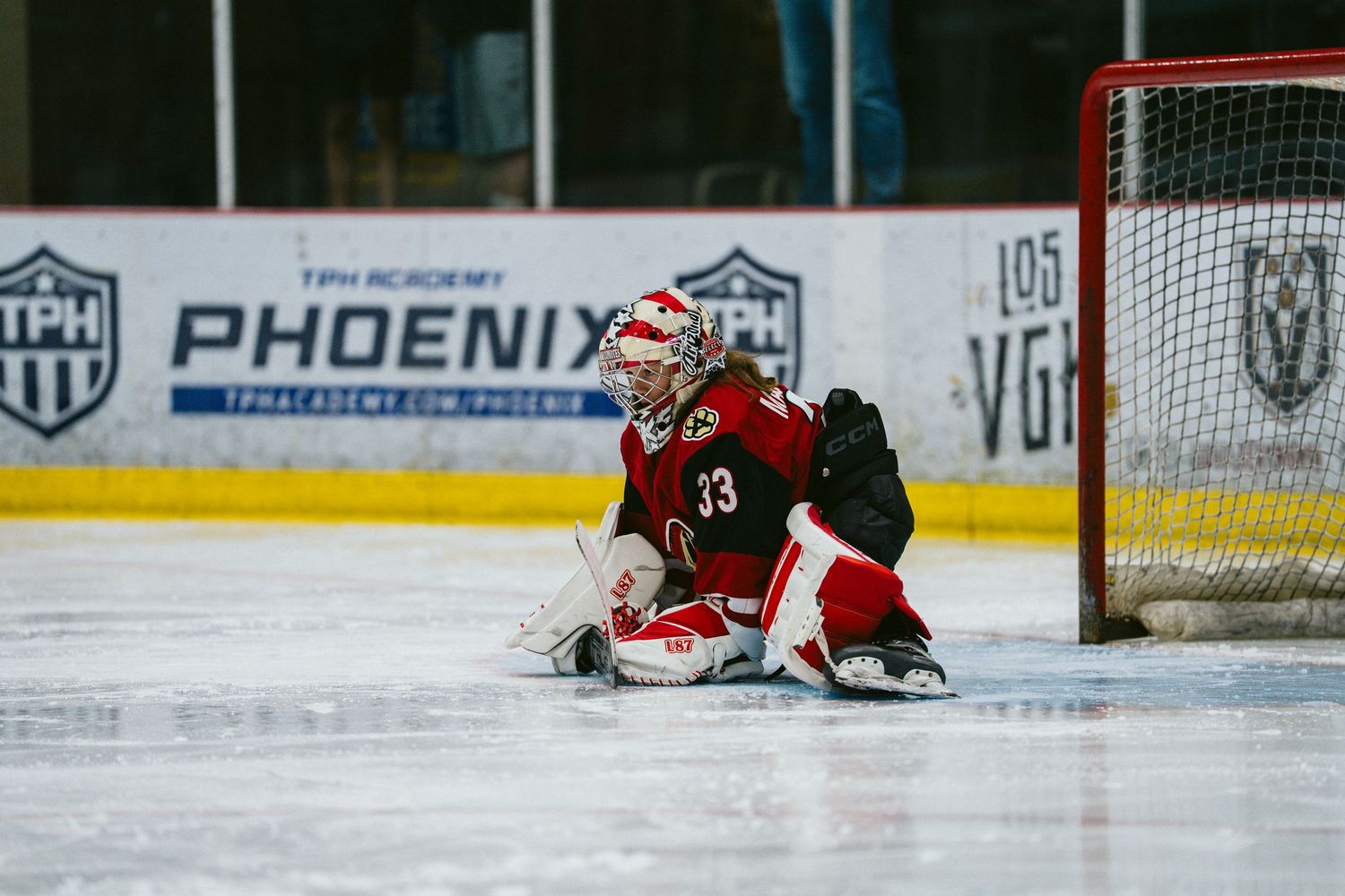 A hockey goalie makes a sliding save on the ice during a game at the Phoenix arena.