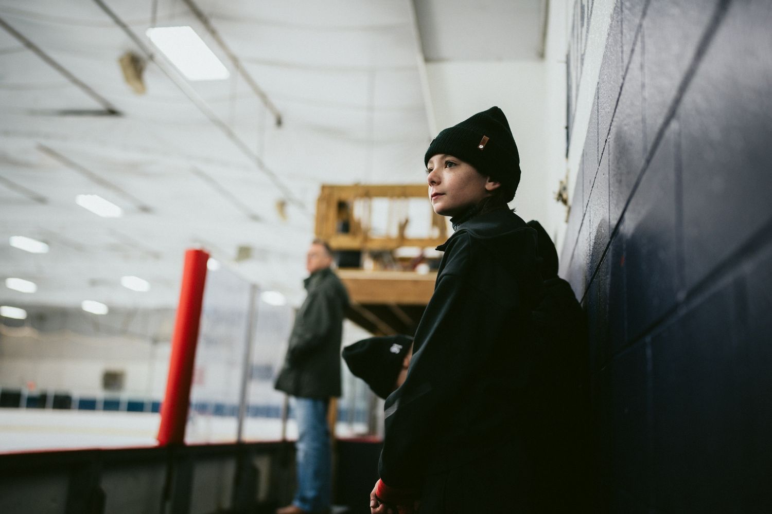 Players sitting on benches watching an ice hockey game through the glass.