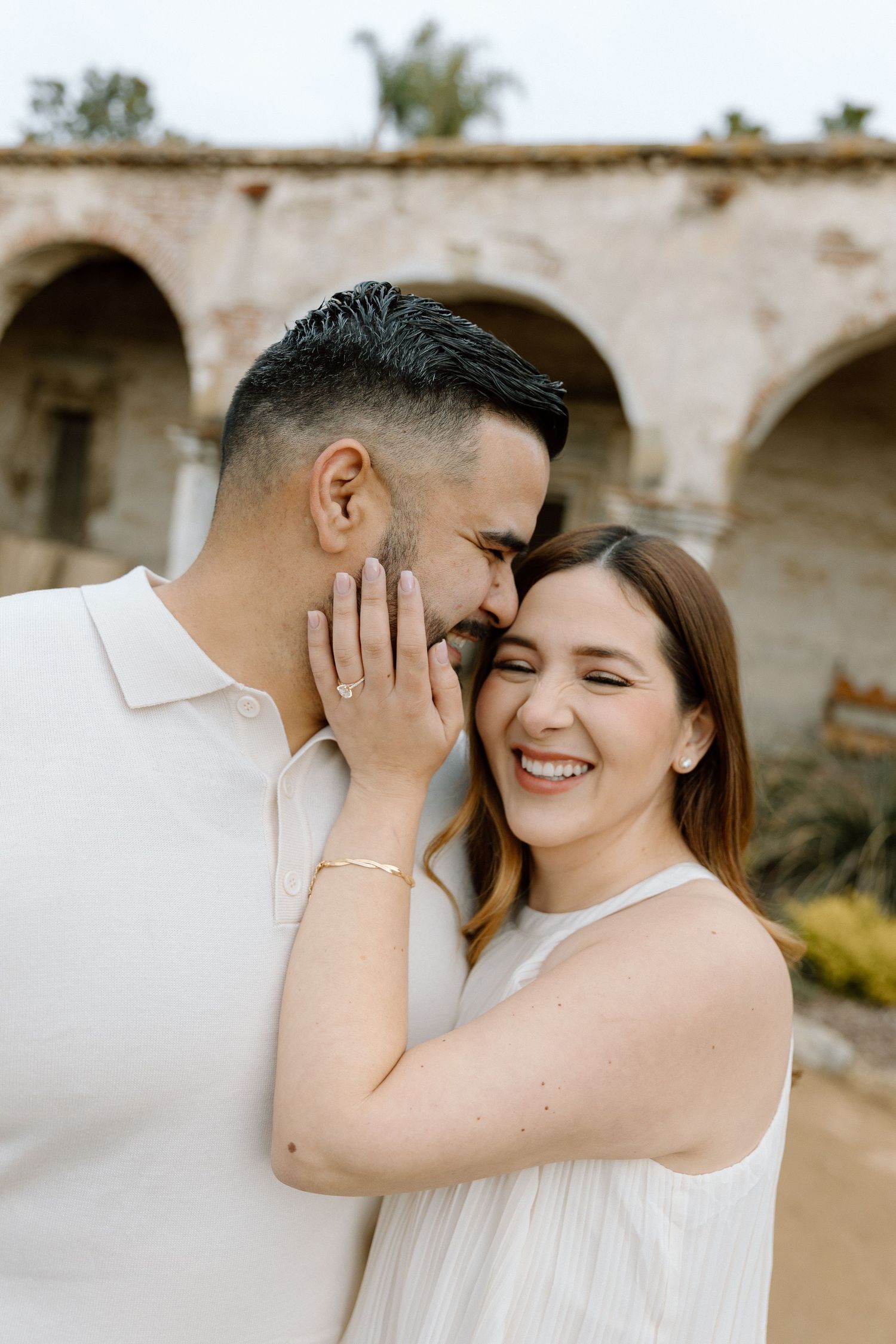 Romantic couple sharing intimate moment against stone archway architecture.