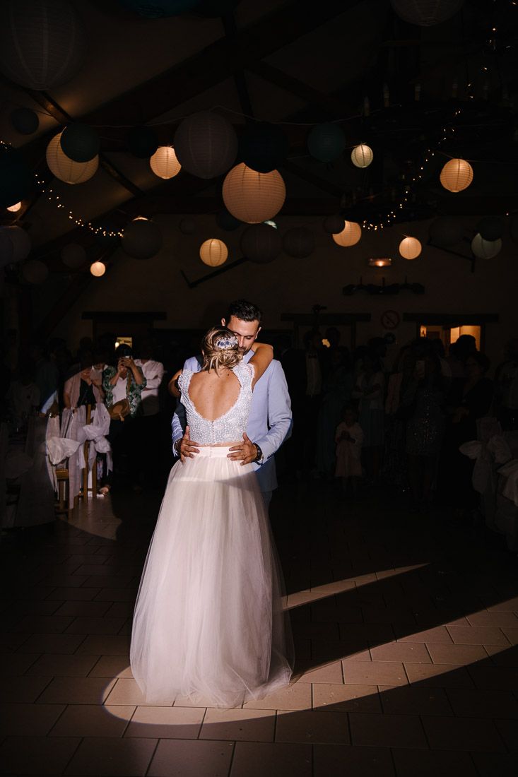 Bride and groom share romantic first dance under glowing paper lanterns in dimly lit wedding reception venue.