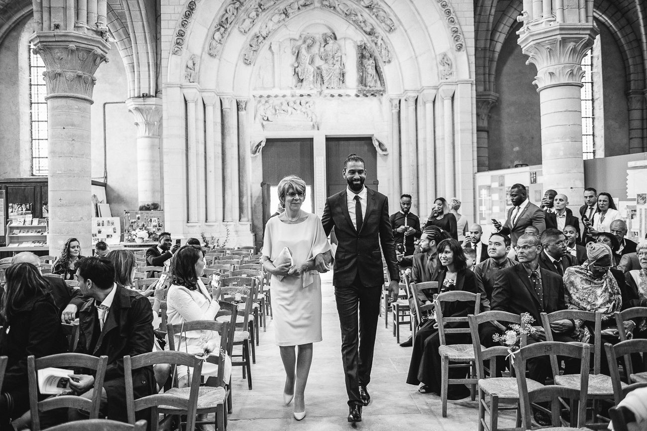 Black and white photo of bride and groom walking down church aisle at wedding ceremony.