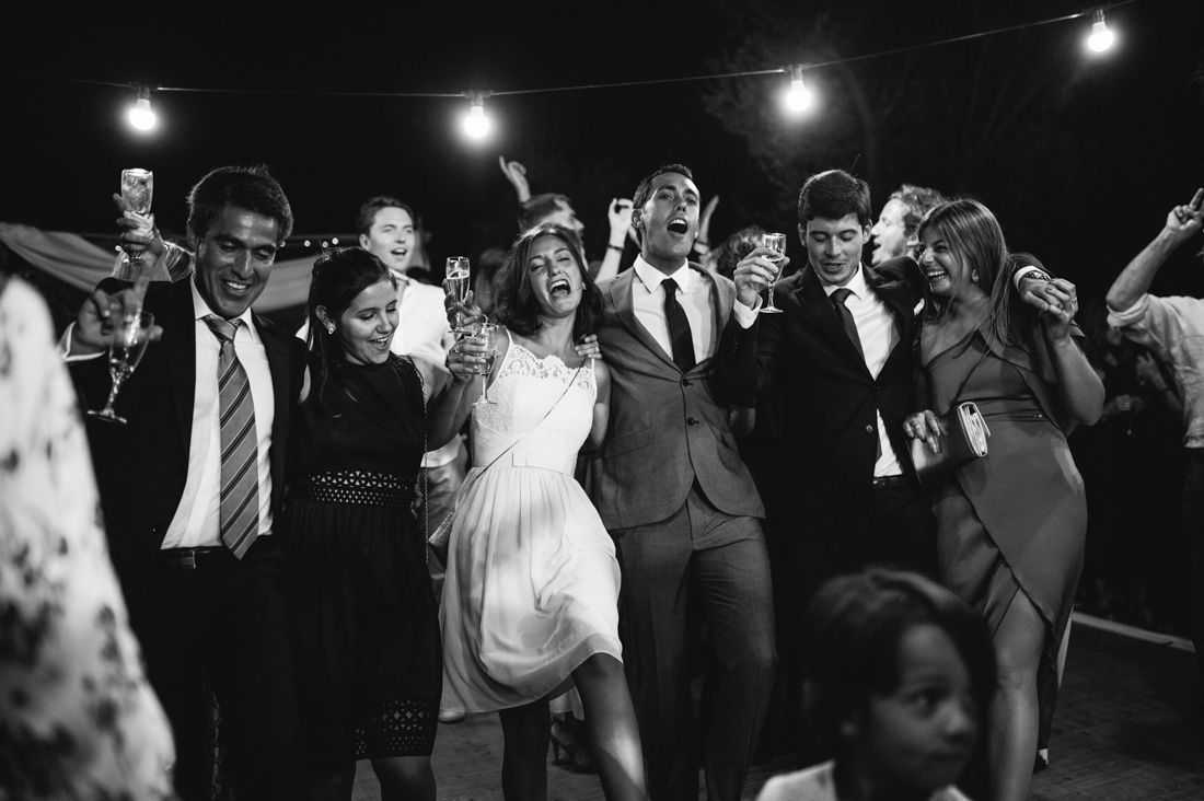 Wedding guests celebrating and dancing together under string lights at a lively reception.