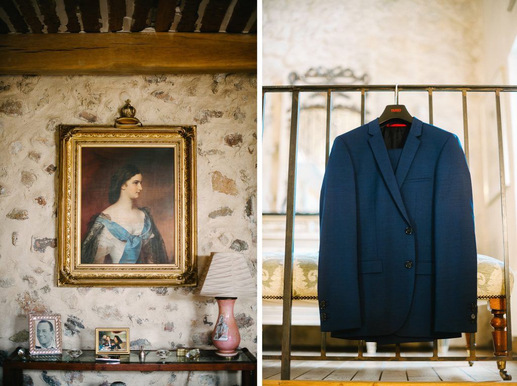 Blue wedding suit jacket hanging on rack beside vintage portrait painting on wall.