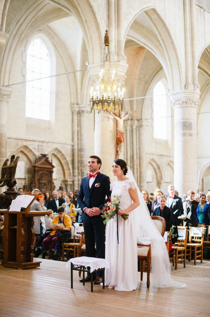 Bride and groom stand at the altar during their wedding ceremony in an elegant stone church with vaulted ceilings.