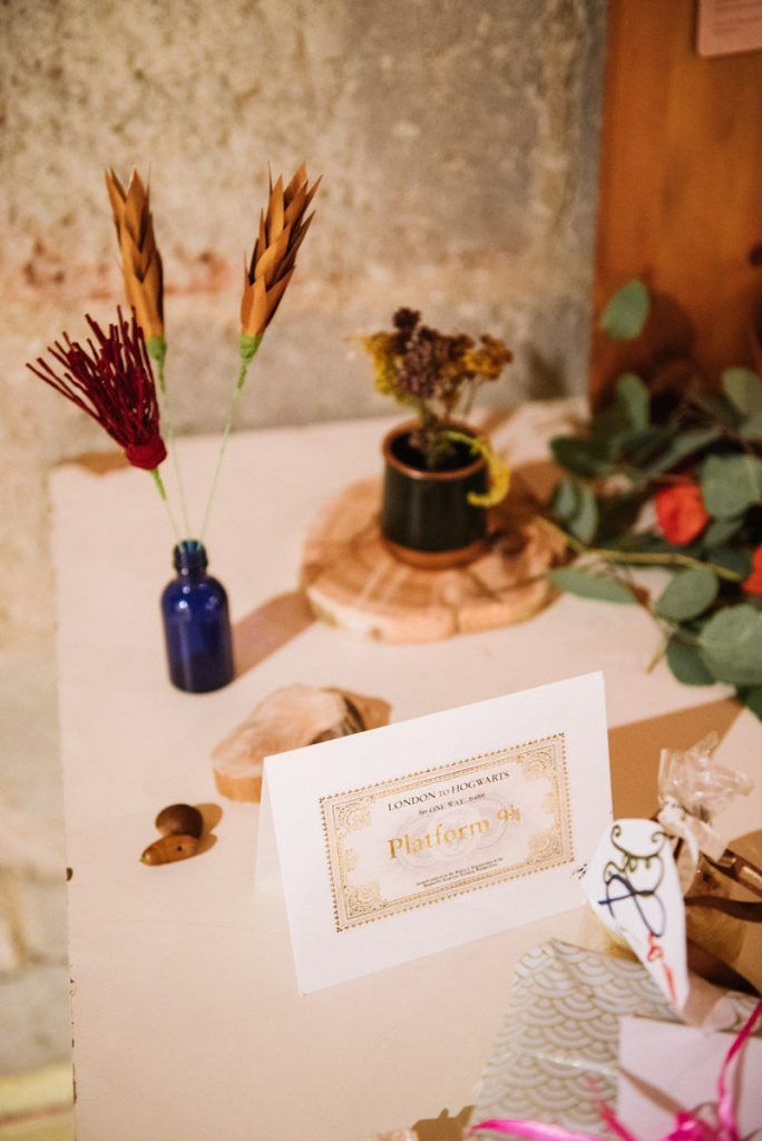 Wedding welcome table with blue bottle, dried flowers, wood slice, and a Harry Potter Platform 9 3/4 sign.