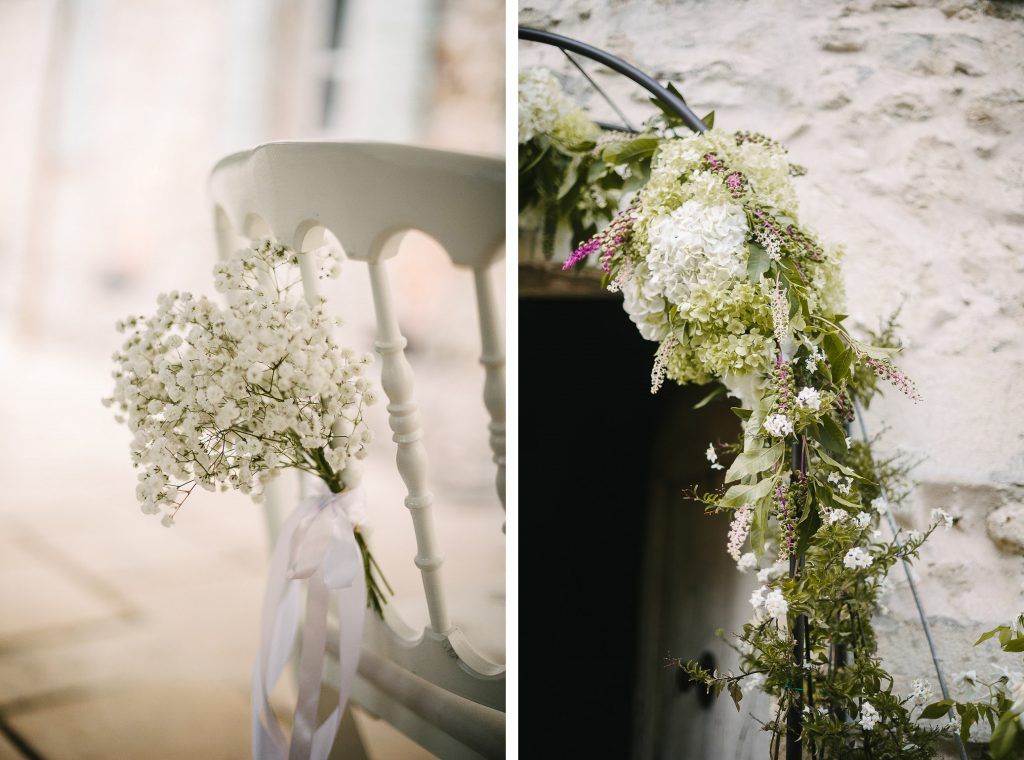 Elegant wedding ceremony decor featuring baby's breath chair bouquet and floral door garland.