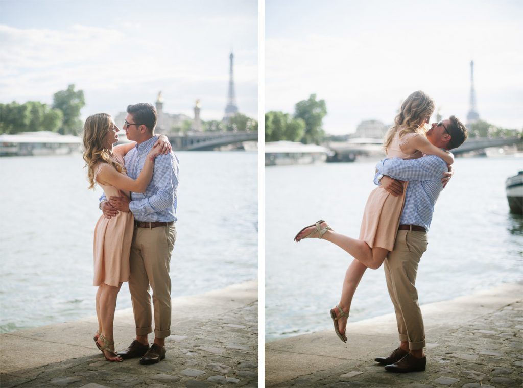 Joyful couple embracing and lifting near the Seine River with the Eiffel Tower visible in Paris.