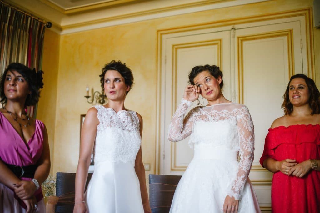 Two brides and guests sharing an emotional moment during wedding ceremony.