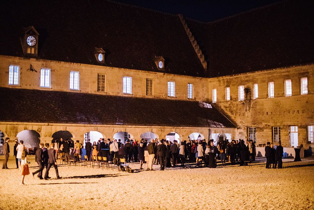 Guests gathered in a historic stone courtyard during an elegant outdoor evening wedding reception.