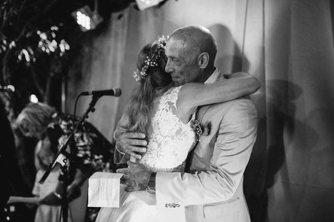 Emotional black and white photo of bride embracing father in tender wedding day moment.