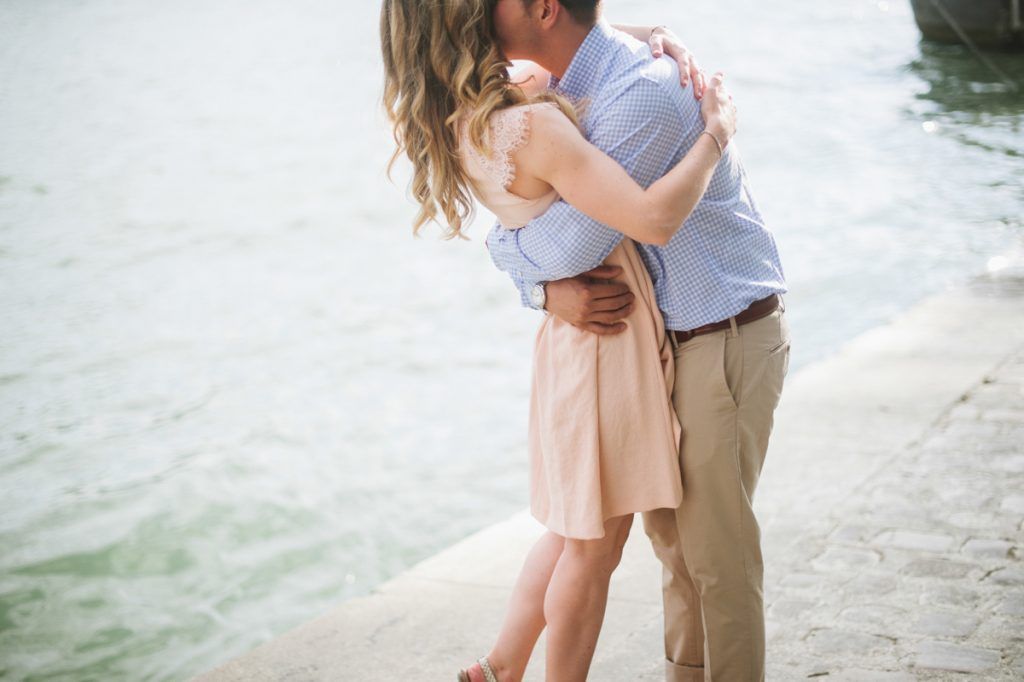 Romantic couple sharing a tender hug by the water's edge in Paris, France.