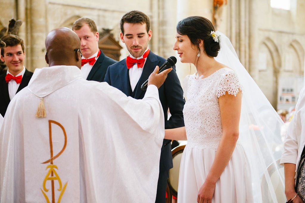 Priest holds microphone for bride during wedding vows exchange in a traditional church ceremony.