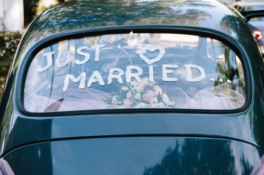 Vintage green car with Just Married sign on rear window.