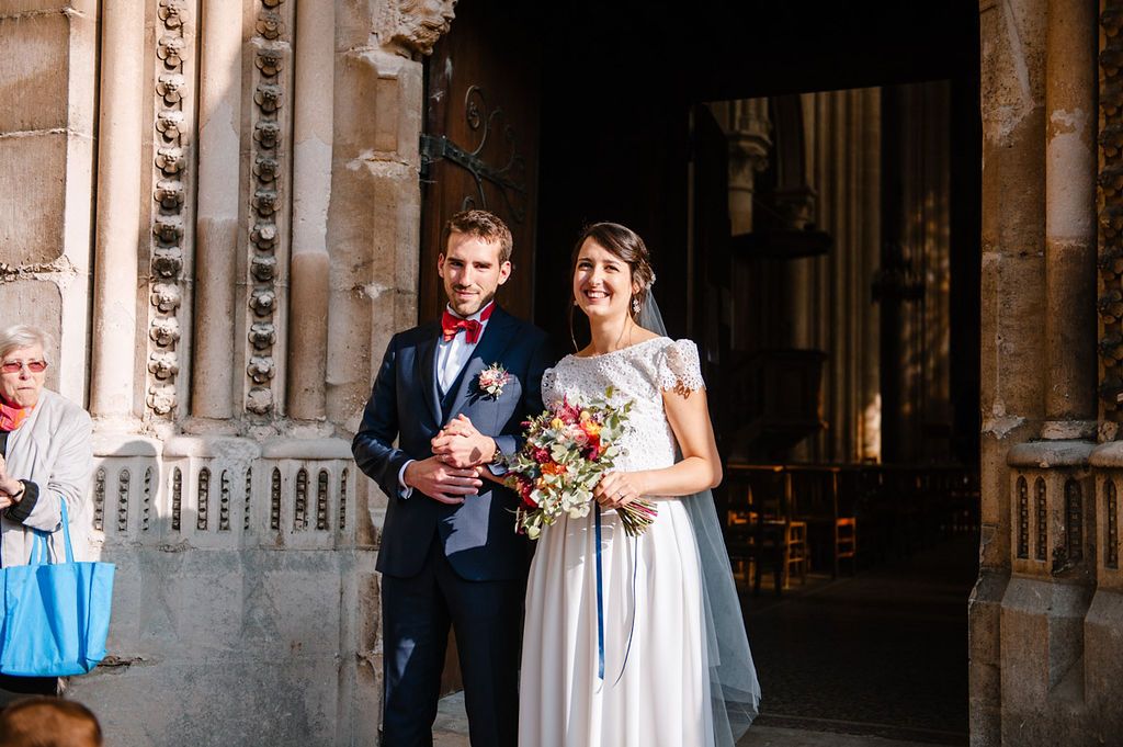 Bride and groom pose together at the entrance of a grand historic stone church after ceremony.