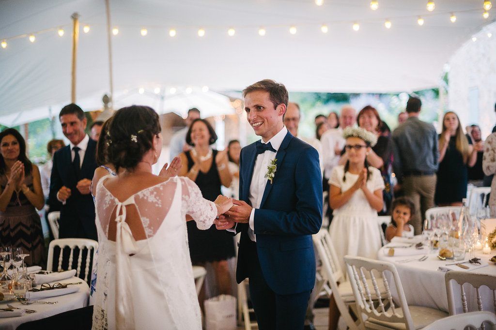 Bride and groom sharing a joyful moment during wedding reception with guests applauding.