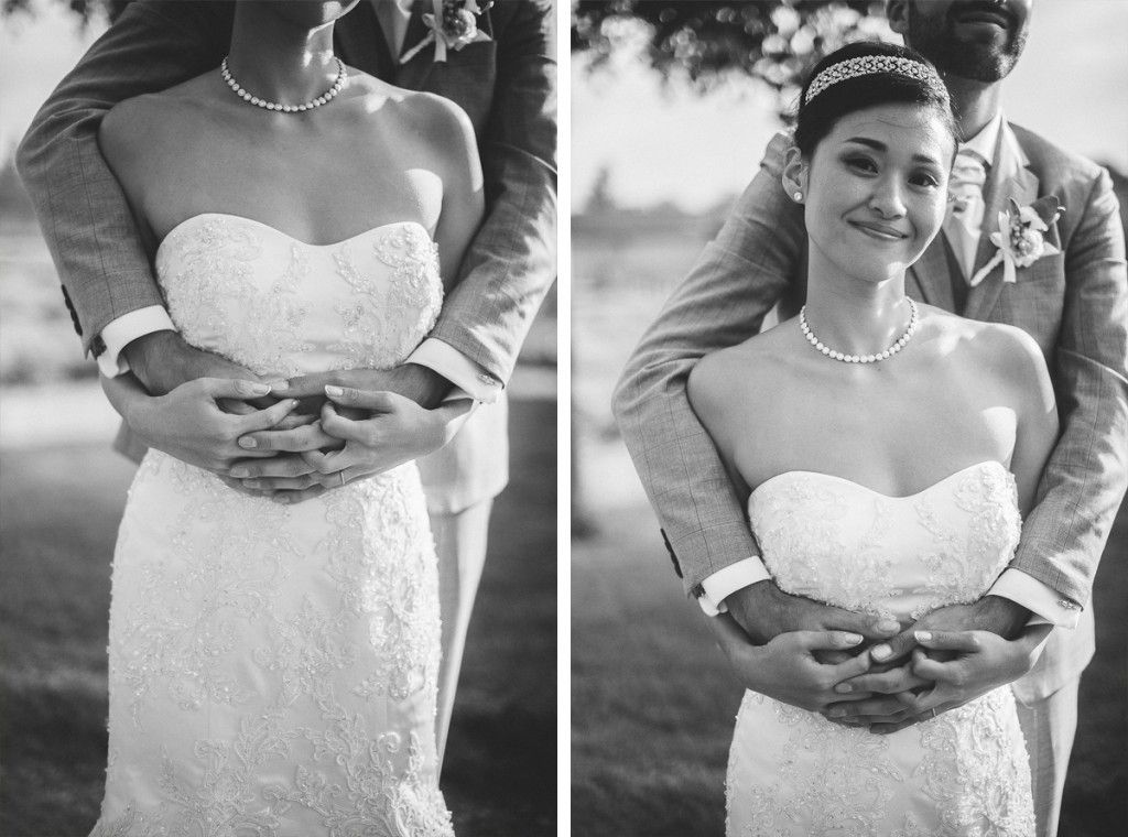 Elegant bride in strapless lace gown smiles softly as groom holds her close.