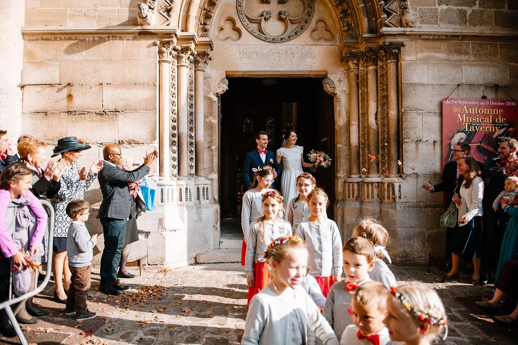Joyful wedding party exits a beautiful historic stone church surrounded by celebrating guests.