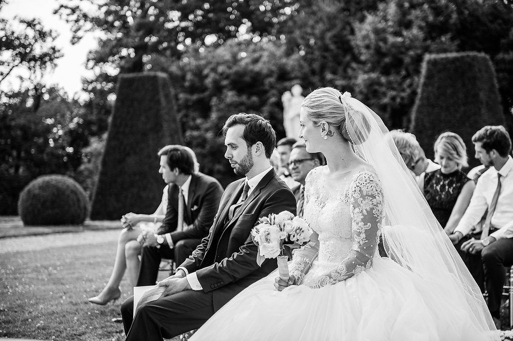 Black and white photo of bride and groom seated together during intimate outdoor garden wedding ceremony.